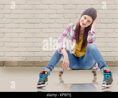 Schöne junge Frau mit einem Skateboard posiert, Sitz auf Skate Stockfoto