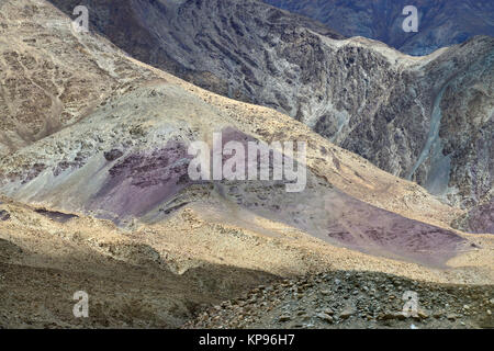 Berghänge von hellen Farben: violett Felsen im Vordergrund, Hintergrund Grauer Rock. Stockfoto