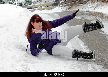 Die Gefahr von Unfällen im Winter - eine Frau hat an einem verschneiten Straße gerutscht Stockfoto