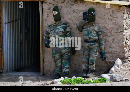 Zwei Puppen von Dummies in militärische Tarnung Uniformen und dunklen Masken auf ihre Köpfe, erzählen von Soldaten in der Nähe der offenen Tür des clay House stehen. Stockfoto