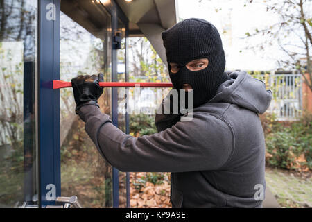 Mann mit Brecheisen öffnen Glastür Stockfoto