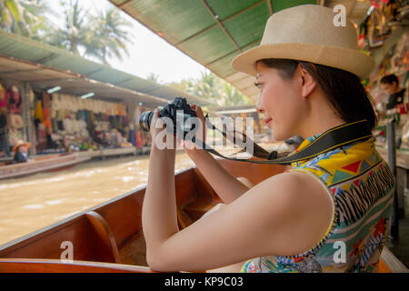 Seitenansicht Foto der jungen schönen Frau Blogger mit Kamera, Video in Damnoen Saduak Markt in Thailand reise. Stockfoto