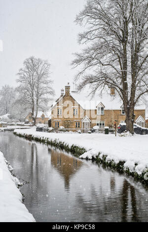 Unteres Schlachtdorf während es im Dezember schneit. Lower Slaughter, Cotswolds, Gloucestershire, England. Stockfoto