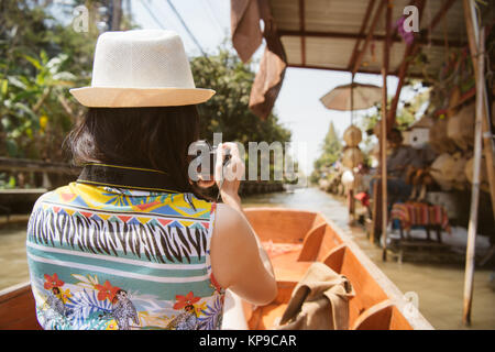 Rückansicht Foto der jungen Frau mit der Kamera unter Bild des Flusses Anbieter bei Damnoen Saduak Markt in Thailand. Stockfoto