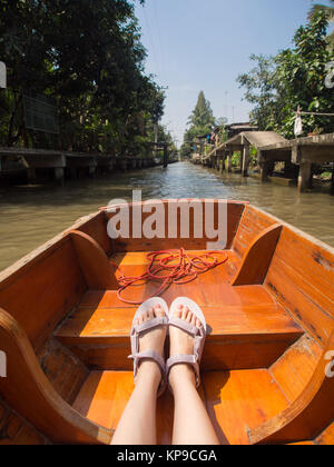 Junge Frau Sandalen sitzen auf Kanal Boot und genießen Blick auf den Fluss in schwimmenden Markt in Asien Thailand Reisen Urlaub. Stockfoto