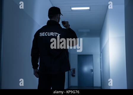 Security Guard mit Taschenlampe in Gebäude Korridor Stockfoto