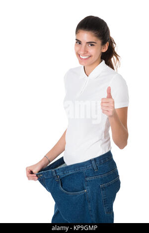 Lächelnde Frau, die Ihre alte Jeans zeigt Nach erfolgreicher Diät Stockfoto