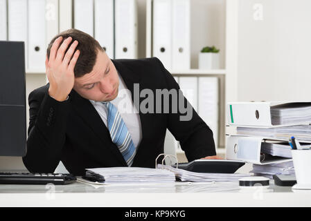 Betonte Buchhalter sitzt am Schreibtisch im Büro Stockfoto