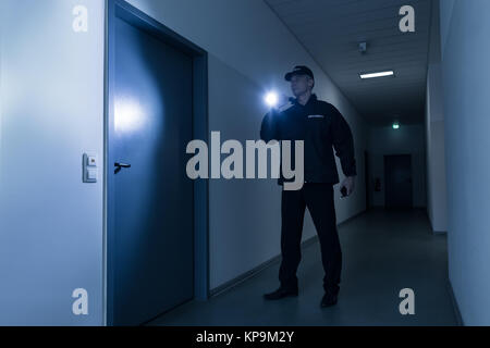 Security Guard mit Taschenlampe stand vor der Tür Stockfoto