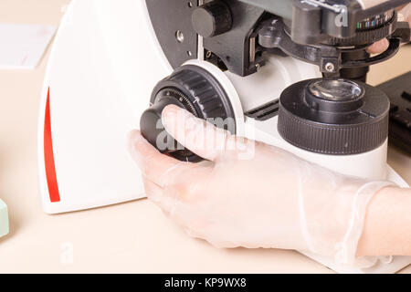 Medizinische oder wissenschaftliche Forscher unter Verwendung eines Mikroskops in Laborumgebung mit Reagenzgläsern und Ausrüstung Stockfoto