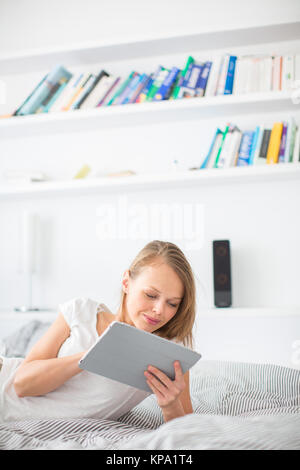 Hübsche, junge Frau im Bett lag, mit Ihrem Tablet-PC Stockfoto