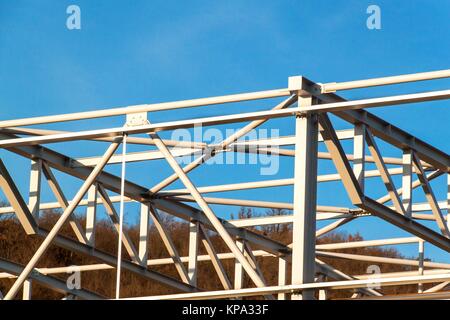 Die Stahlkonstruktion ist im Bau. Installation von Metall Hallen. Arbeiten in der Höhe. Einen sonnigen Tag auf einer Baustelle Stockfoto