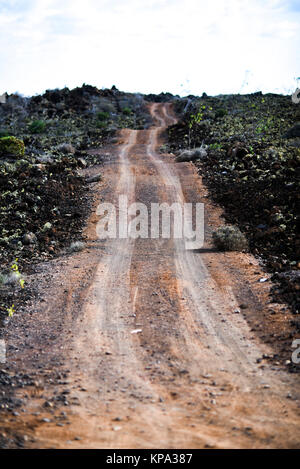 Sandweg unter Lavafelder auf Lanzarote, Kanarische Inseln. Stockfoto