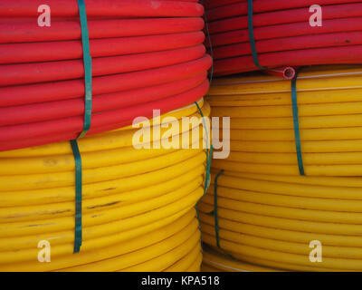 Riesige Spulen von gelben und roten Kabel sind eine über der anderen, Rot auf der Oberseite, Gelb von unten gestapelt. Stockfoto