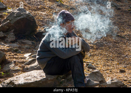 Indische Mann sitzt rauchen Zigarette in Dharamkot, Indien Stockfoto