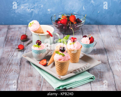 Hausgemachte Erdbeere und Kirsche Eis in der Waffel Lagerringe und -kegel auf einem keramischen Fach Vintage Stimmung serviert. Stockfoto