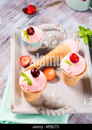 Hausgemachte Erdbeere und Kirsche Eis in der Waffel Lagerringe und -kegel auf einem keramischen Fach Vintage Stimmung serviert. Stockfoto