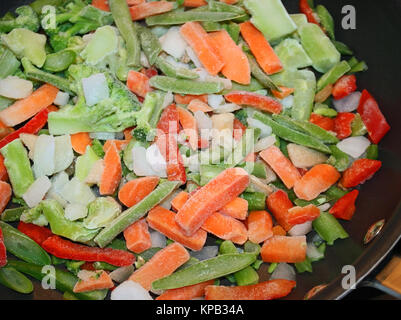 Ein Sortiment von rohem Gemüse in einem antihaftbeschichtete Pfanne zum Kochen bereit. Gefrorene Möhren, Paprika, Bohnen, Zwiebeln, Broccoli Stockfoto