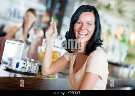 Model Release, Lachende, Junge Frau Sitzt eine der Theke Im Kaffeehaus Und Raucht - junge Frau Rauchen in der cafeteria Stockfoto