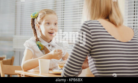 Mädchen mit Zopf mit ihrer Mama im Cafe - jugendlich fühlt sich überrascht Stockfoto