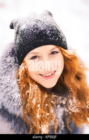 Porträt der schönen jungen Frau im Winter schneebedeckten weißen Hintergrund. In der Nähe der weiblichen lächelndes Gesicht mit wunderschönen langen Ingwer Haar. Stockfoto