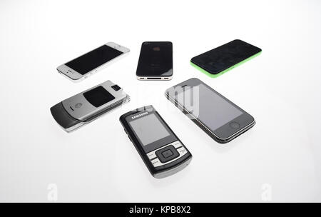 Eine Mischung aus alten Handys wie iPhone, Motorola und Samsung auf einem weißen Hintergrund. Stockfoto