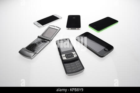 Eine Mischung aus alten Handys wie iPhone, Motorola und Samsung auf einem weißen Hintergrund. Stockfoto