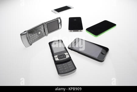 Eine Mischung aus alten Handys wie iPhone, Motorola und Samsung auf einem weißen Hintergrund. Stockfoto