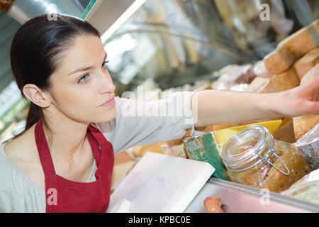 Gerne Frau mit verschiedenen Käse an Bord in Store Stockfoto