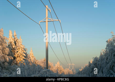 High-Voltage Power Transmission Line, vorbei an einer Lichtung im Wald. Säulen, Drähte und Bäume sind mit einer dicken Eisschicht bedeckt, Sn Stockfoto