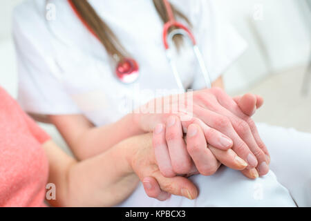 Krankenschwester die Hand des älteren Frau im Rollstuhl Stockfoto