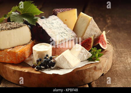 Köstliches Käseplatte mit einem breiten Sortiment von Weiche und halbharte Käse mit in Scheiben geschnittenen Süße frische Feigen und Trauben auf einem rustikalen Holztisch mit Hintergrund Schatten serviert Stockfoto