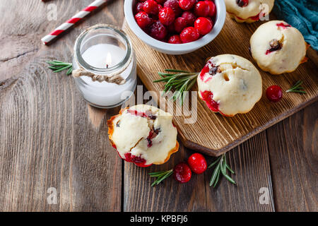 Muffins mit Preiselbeeren und Schokolade, Flaschen mit Milch und Papier Trinkhalme und Kerzen auf einem dunklen Holztisch Stockfoto