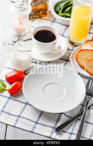 Weiße Platte, Kaffee und Orangensaft auf einem weißen Holztisch. Serviert zum Frühstück Stockfoto