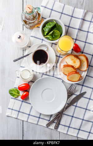 Weiße Platte, Kaffee und Orangensaft auf einem weißen Holztisch. Zum Frühstück servieren. Ansicht von oben Stockfoto