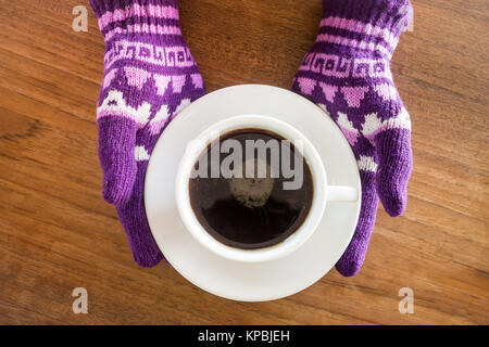 Behandschuhten Hände, die Tasse Kaffee Stockfoto