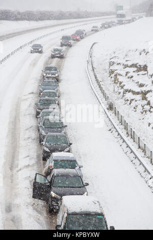 Autos und Lastwagen in der Warteschlange und im Schnee auf rutschiger Fahrbahn der A 417 außerhalb Cirencester in Großbritannien fest. Stockfoto