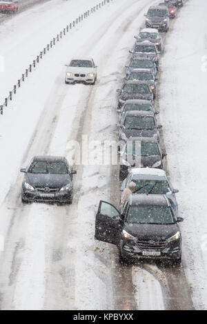 Autos und Lastwagen in der Warteschlange und im Schnee auf rutschiger Fahrbahn der A 417 außerhalb Cirencester in Großbritannien fest. Stockfoto