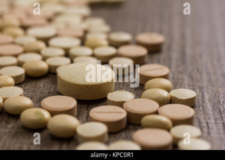 Haufen sortierte beige Kapseln auf Holztisch. Stockfoto