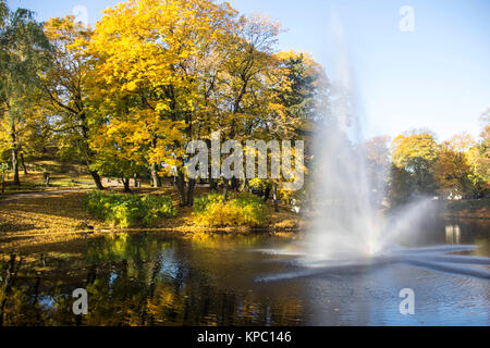 Brunnen und Regenbogen in Riga Kanal, fließt durch die Bastion Park Herbst Hintergrund mit farbigen Blätter (Bastejkalns). Lettland Herbst Stockfoto