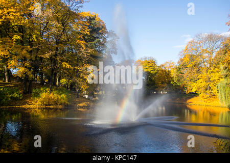 Brunnen und Regenbogen in Riga Kanal, fließt durch die Bastion Park Herbst Hintergrund mit farbigen Blätter (Bastejkalns). Lettland Herbst Stockfoto