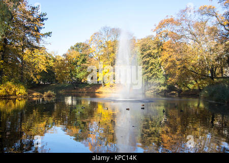 Brunnen und Regenbogen in Riga Kanal, fließt durch die Bastion Park Herbst Hintergrund mit farbigen Blätter (Bastejkalns). Lettland Herbst Stockfoto