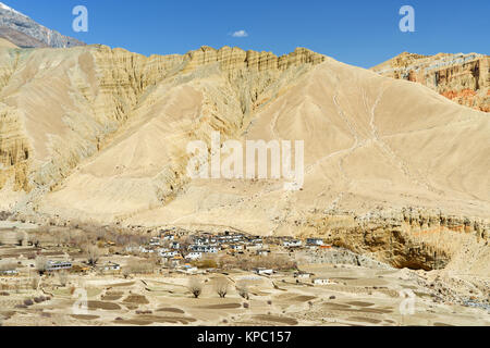 Dorf Ghemi, Oberer Mustang region, Nepal, gesehen aus einer Entfernung inmitten einer kargen wüstenhaft Landschaft. Stockfoto