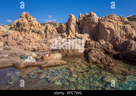 Frau nimmt ein Sonnenbad an der idyllischen Küste der Costa Paradiso, Porphyr Felsen, Sardinien, Italien, Mittelmeer, Europa Stockfoto