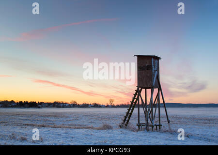 Angesprochen für die Jagd auf Rehe bei Sonnenaufgang ausblenden in schneebedeckten Feld im Winter, Niedersachsen, Deutschland Stockfoto