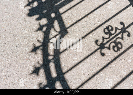 Abstrakte Schatten von schmiedeeisernen Tor auf Beton Gehweg Stockfoto