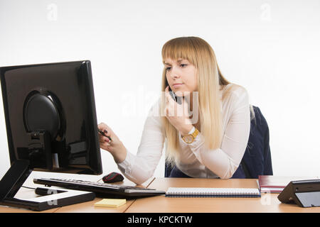 Geschäftsfrau mit Konzentration arbeitet in den Computer während des Gesprächs am Telefon Stockfoto