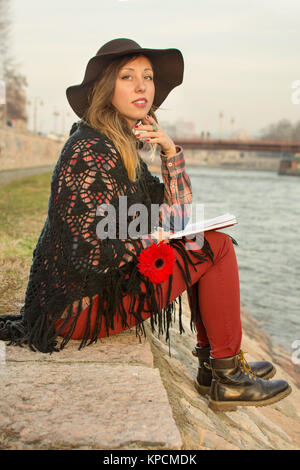 Brunette Mädchen mit einem Buch am Flussufer Stockfoto