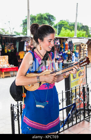 ANTIGUA, GUATEMALA - Dec 24, 2015: junge schöne Frau, die Gitarre spielen auf der Straße von Antigua am 24.Dezember 2015. Guatemala. Stockfoto