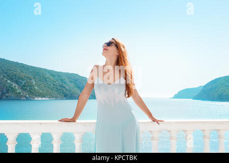 Schönes Modell in Dress lehnte sich auf weißen Zaun der Balkon mit Blick auf die tropischen Bucht auf Hintergrund. Stockfoto